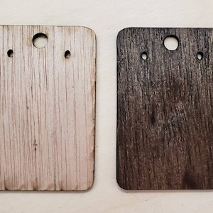 May include: Two wooden earring display cards, one is natural wood and the other is stained dark brown. Both cards have three holes for earrings.
