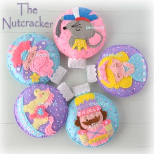 May include: Handmade felt Christmas ornaments featuring characters from The Nutcracker ballet. The ornaments include a mouse king, a ballerina, a horse, a nutcracker soldier, and a fairy, all with sequin details.