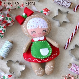 Könnte beinhalten: Handgemachte Lebkuchenfrau-Puppe aus Filz mit rotem Kleid, grüner Schürze und roter Schleife. Die Puppe hat weißes Haar mit Streuseln und ein lächelndes Gesicht. Das Bild enthält Ausstecher, Zuckerstangen und Schleifenband. Der Text "PDF PATTERN" ist sichtbar.