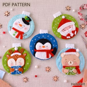 Könnte beinhalten: Weihnachtsschmuck aus Filz in Form eines Schneemanns, Weihnachtsmanns, Pinguins, Rentiers und Bären. Jeder runde Schmuck hat eine weiße Oberseite und ist mit festlichen Farben verziert. Die Ornamente haben einzigartige Designs und sind mit Schneeflocken verziert.