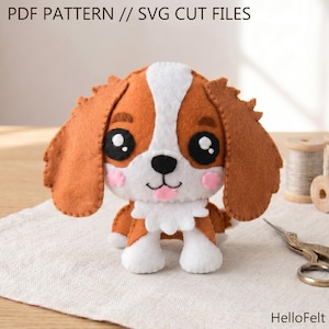 May include: A handmade felt dog toy with brown and white fur, large black eyes, and pink cheeks. The text "PDF PATTERN // SVG CUT FILES" is at the top. The toy is on a white cloth with sewing supplies in the background.