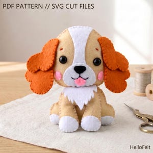 May include: A handmade felt dog with tan, white, and orange accents. The dog has large black eyes, pink cheeks, and a pink tongue. The image includes the text "PDF PATTERN // SVG CUT FILES".