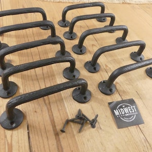 May include: A set of ten black metal cabinet handles with a textured finish, each featuring two circular mounting plates with screw holes. A small pile of metal screws and a square black label with the white text MIDWEST CRAFT HOUSE are included.