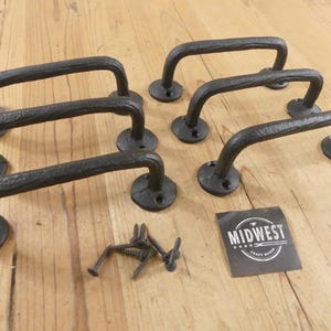 May include: A set of five black cast iron pull handles with a textured, branch-like finish, each featuring two circular mounting plates with screw holes. A small square black label with the white text MIDWEST CRAFT HOUSE and several screws.