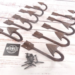 May include: A collection of rustic arrow-shaped hooks in a dark brown finish. The hooks are made of metal and include mounting screws. The image also shows a black and white Midwest Craft House logo.
