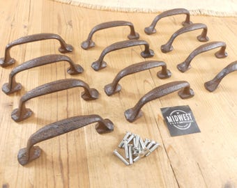 May include: A collection of ten dark brown, textured cast iron drawer pulls with curved handles and rectangular mounting bases. A small pile of silver-coloured metal screws is included, along with a black square label featuring the text MIDWEST.