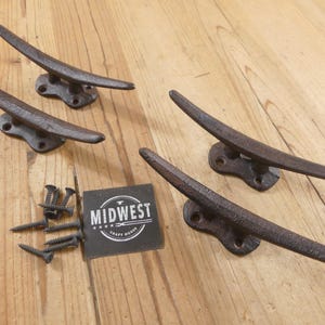 May include: Four cast iron cleats with a rustic, weathered finish, perfect for nautical decor. Includes mounting screws and a tag with the text "MIDWEST CRAFT HOUSE".