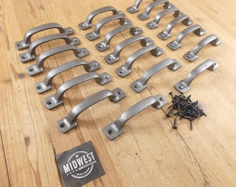 May include: A collection of fifteen grey metal drawer pulls with a textured finish, each featuring two screw holes at the ends. A small pile of black screws is included, along with a square black label featuring the text MIDWEST CRAFT HOUSE.