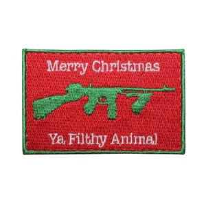 May include: Embroidered patch with a red background and green border. The patch features the text "Merry Christmas" above a green machine gun graphic, and the phrase "Ya Filthy Animal" below.