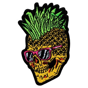 Pode incluir: Patch bordado com uma caveira amarela com um design de abacaxi. A caveira usa óculos de sol rosa e tem folhas verdes de abacaxi no topo. O patch tem uma borda preta.
