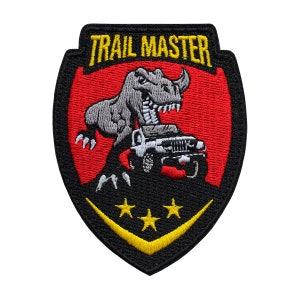 May include: Black and red embroidered patch with a yellow "TRAIL MASTER" text. A gray dinosaur is depicted stomping on a white jeep with three yellow stars below.