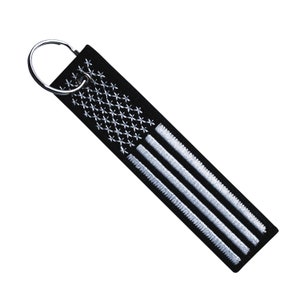 May include: Black key chain with a white embroidered American flag design.