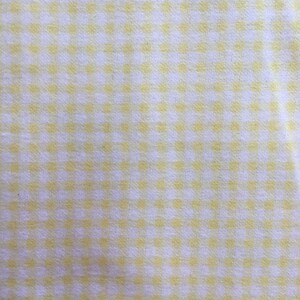 May include: A white fabric with a yellow gingham pattern.