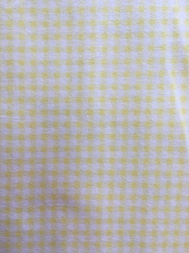 May include: A white fabric with a yellow gingham pattern.