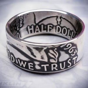 Könnte beinhalten: Ein silberner Ring aus einer 50-Cent-Münze von 1963. Der Ring trägt die Inschrift "IN GOD WE TRUST" und "HALF DOLLAR" um das Band.