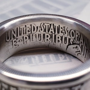 May include: Close-up of a silver ring with the inscription "UNITED STATES OF AMERICA E PLURIBUS UNUM" engraved on the inside.
