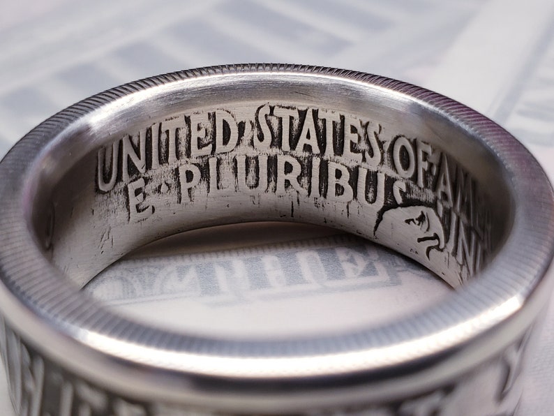 May include: Close-up of a silver ring with the inscription "UNITED STATES OF AMERICA E PLURIBUS UNUM" engraved on the inside.