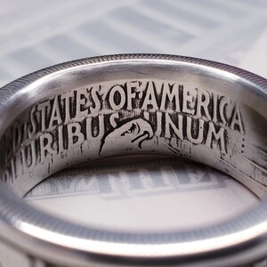 May include: Close-up of a silver ring with the inscription "United States of America E Pluribus Unum" engraved on the inside.