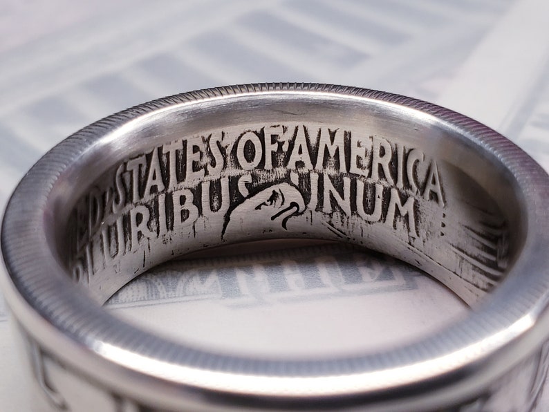 May include: Close-up of a silver ring with the inscription "United States of America E Pluribus Unum" engraved on the inside.