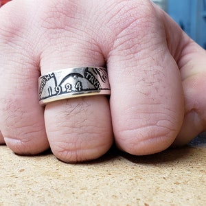 May include: A silver ring made from a 1924 silver coin. The ring features the words "In God We Trust" and "Liberty" on the band.