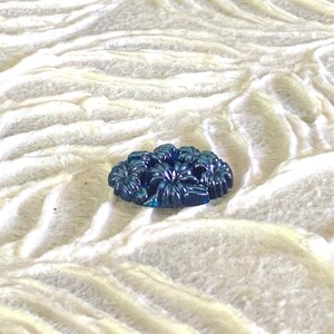 May include: A dark blue glass button with a floral design.