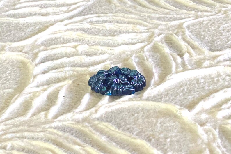 May include: A dark blue glass button with a floral design.