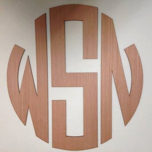 May include: A wooden monogram with the letters W, S, and N in a circle. The letters are cut out of the wood and the background is a light wood color.