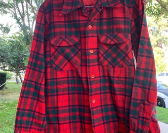 May include: Red and black plaid flannel shirt with a button-up front and two chest pockets. The shirt has a label that reads "Woolrich, Woolrich, Inc., New York, N.Y."