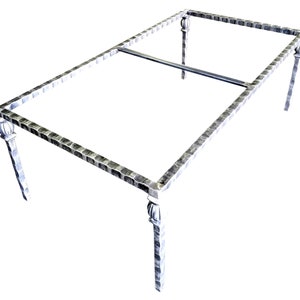 May include: A silver metal table base with a hammered finish and decorative finials on the legs. The base is designed to support a glass tabletop.