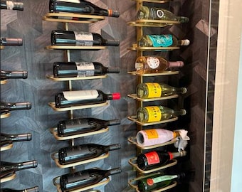 May include: A gold metal wine rack with multiple rows of wine bottles. The rack is mounted on a wall with a dark wood paneling background.