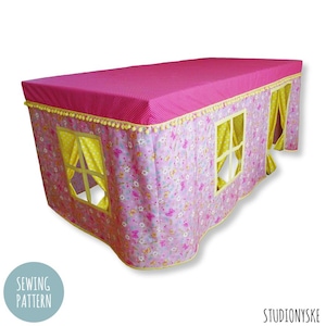 Puede incluir: Un dosel de cama de tela rosa y amarilla, con un patrón floral y ribete de pompones. El dosel tiene dos ventanas con cortinas amarillas.