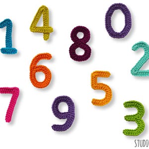 May include: Crocheted numbers 0 through 9 in various colors. The numbers are arranged in a random pattern on a white background.