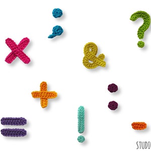 May include: A collection of colorful, crocheted punctuation marks, including an ampersand, question mark, and exclamation point, against a white background. The handmade symbols are in various colors like pink, green, and teal. The image includes the text "STUDIONYSKE".