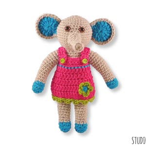 May include: A crocheted elephant toy wearing a pink dress with a green flower and blue accents.