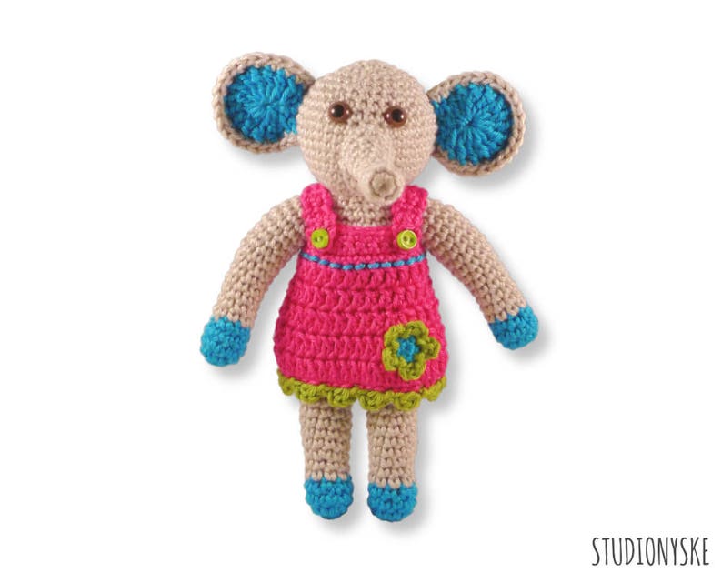 May include: A crocheted elephant toy wearing a pink dress with a green flower and blue accents.
