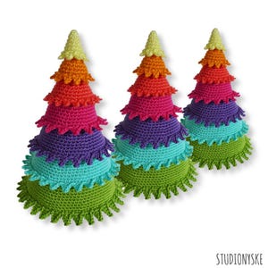 Puede incluir: Tres árboles de Navidad de crochet arcoíris, cada uno con seis capas de diferentes colores, comenzando con una base verde claro y terminando con una parte superior amarilla.