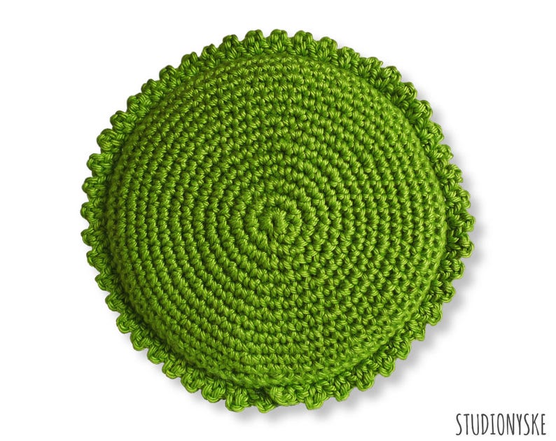 Puede incluir: Un coj&iacute;n redondo de crochet de color verde con un borde festoneado.