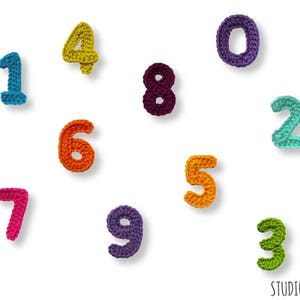 May include: Crocheted numbers 0 through 9 in various colors. The numbers are arranged in a random pattern on a white background.