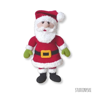 May include: A crocheted Santa Claus doll with a red suit, white beard, and black boots. The doll is wearing a green hat with a white pom-pom.