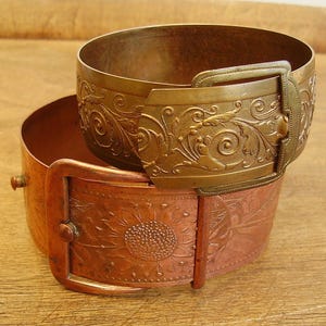 Peut inclure: Deux bracelets en métal vintage avec des motifs ornés. Le bracelet du haut est doré et présente un motif floral avec une fermeture à boucle. Le bracelet du bas est de couleur cuivre et présente un motif de tournesol avec une fermeture à boucle.