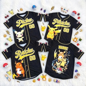 Op de afbeelding: Vier zwarte honkbalshirts met gele accenten en karakterontwerpen. Elk shirt heeft een ander Pokémon-personage: Pichu, Pikachu, Raichu en een aangepast "NAME"-ontwerp. De shirts zijn versierd met verschillende Pokémon-accessoires.
