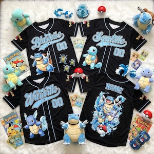 May include: Black baseball jerseys with light blue accents and Pokémon character designs. The jerseys feature the names "Blastoise", "Squirtle", "Wartortle", and "Name", along with the number "00". Plush toys, trading cards, and Poké Balls are also present.