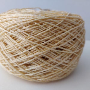 May include: A ball of cream-coloured yarn with a subtle shimmer.