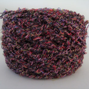 May include: A skein of yarn in a multi-coloured mix of black, pink, red, purple, and yellow. The yarn is a fuzzy, textured type.
