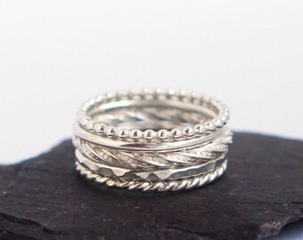 May include: A set of four silver stacking rings with different textures, including beaded, twisted, and hammered.