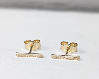 May include: A pair of gold bar stud earrings with a textured finish.