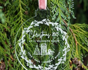 May include: Clear glass Christmas ornament with a white wreath design and the text "Christmas 2023 at 21 Rudolph Road John - Paul - Gemma - Bingo".