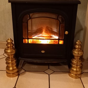Peut inclure: Une cheminée électrique noire avec un effet de flamme réaliste. Deux embouts décoratifs en métal doré sont de chaque côté de la cheminée.