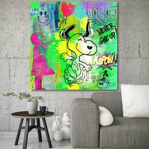 Peut inclure: Une toile carrée représentant une illustration de style graffiti vibrante avec un chien de dessin animé, une silhouette rose et un cœur rouge. L'œuvre comprend des éléments textuels audacieux "LIFE IS BEAUTIFUL", "BOOOOM" et "KAPOW" aux couleurs vives.
