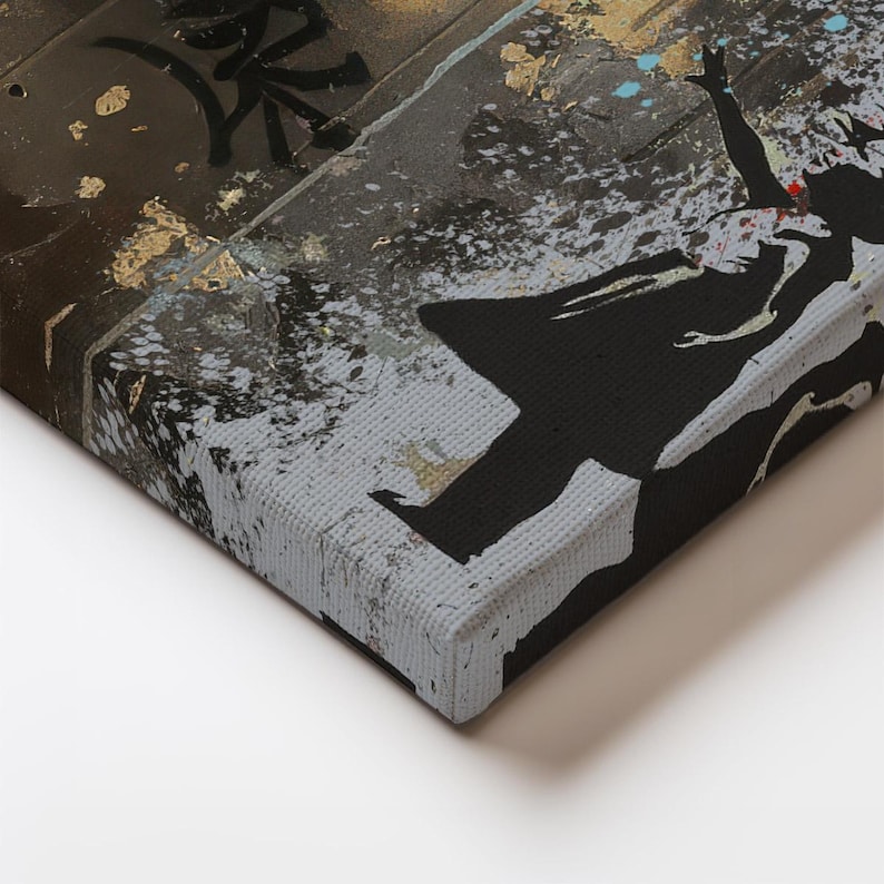 May include: A canvas wall art print featuring a black silhouette of a person with arms raised against a textured background of dark gray, brown, and gold leaf accents. The artwork displays a distressed, urban aesthetic with splattered paint details.